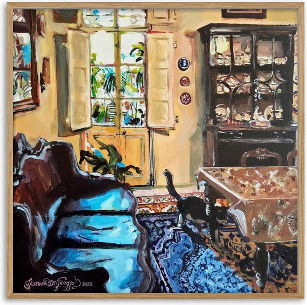 Kamra tal-pranzu bil-bitħa fl-isfond by Mariam De Giorgio — an ochre dining room with a china dresser, blue rug and a black cat by the courtyard door.