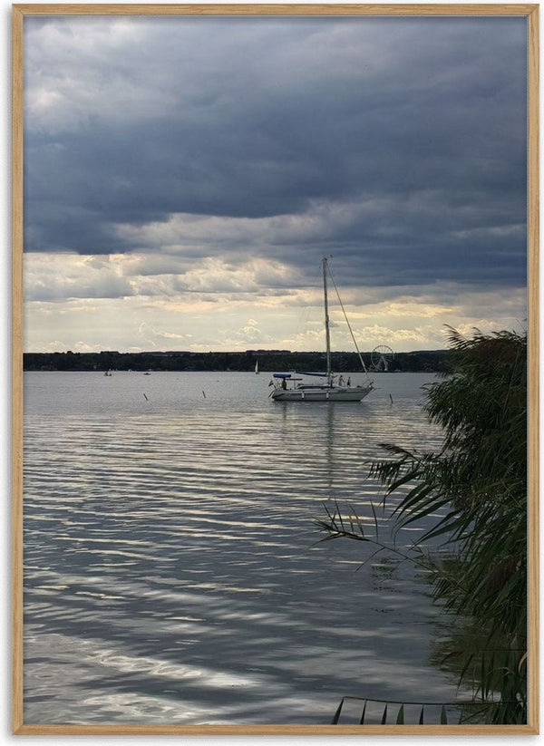 Light Reaching the Water by Bora Kőhalmi - a white sailboat under a heavy grey cloud with a band of light over Lake Balaton