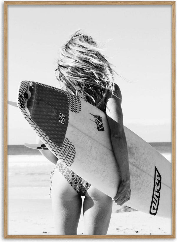 Woman in swimwear holding a surfboard on the beach, showcasing Surfers Fashion’s coastal style.