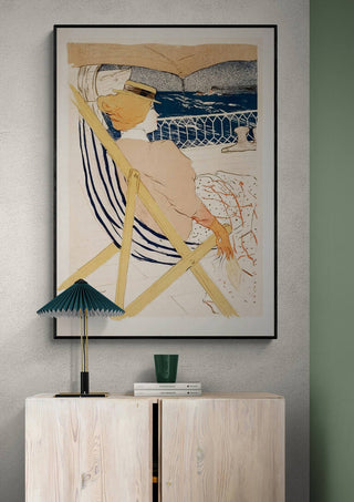 Framed print of "La PassagAure Du 54" by Lautrec hanging above a light wood cabinet with decor items.