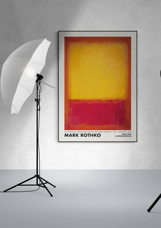 Framed Rothko Yellow on Red print displayed on a white wall between two studio lights.