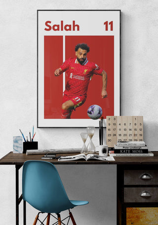 Salah Liverpool Football Poster featuring Mohamed Salah in action wearing a red Liverpool kit, displayed above a desk.