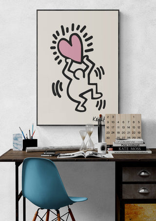Poster of Keith Haring's Hearthead artwork hanging above a modern desk with art supplies and books.
