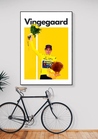 Jonas Vingegaard Cycling Poster featuring him celebrating in a yellow jersey, displayed above a bicycle.